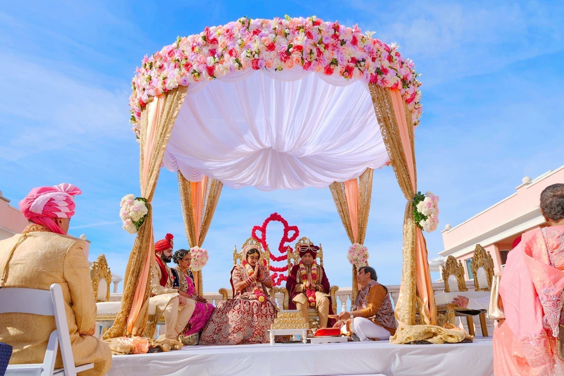A couple under a floral wedding mandap